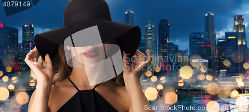 Image of beautiful woman in black hat over singapore city