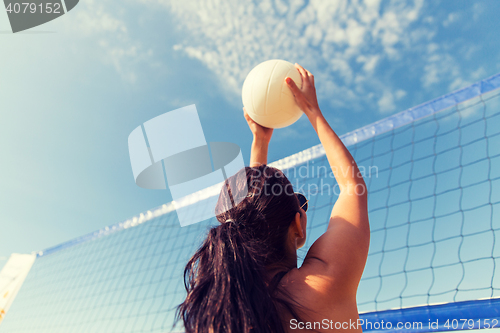 Image of young woman with ball playing volleyball on beach