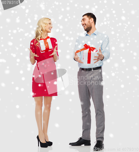 Image of happy couple with christmas gift boxes over snow