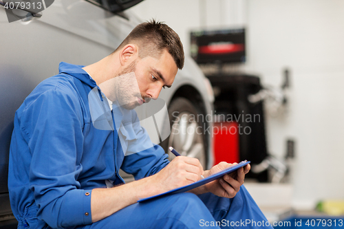 Image of auto mechanic man with clipboard at car workshop