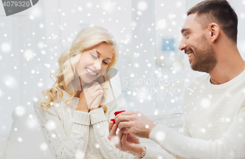 Image of happy man giving engagement ring to woman at home