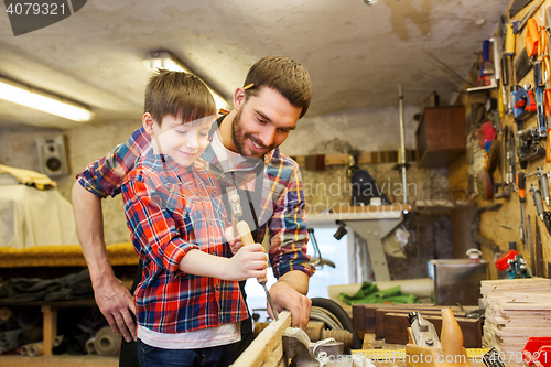 Image of father and son with chisel working at workshop