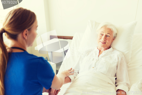 Image of doctor or nurse visiting senior woman at hospital