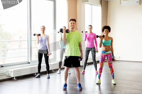 Image of group of smiling people exercising with dumbbells