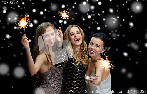 Image of happy young women with sparklers over snow