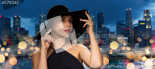 Image of beautiful woman in black hat over singapore city