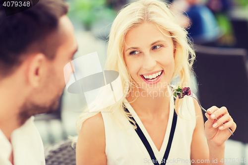 Image of happy couple eating dinner at restaurant terrace