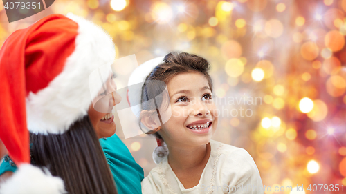 Image of happy mother and little girl in santa hats