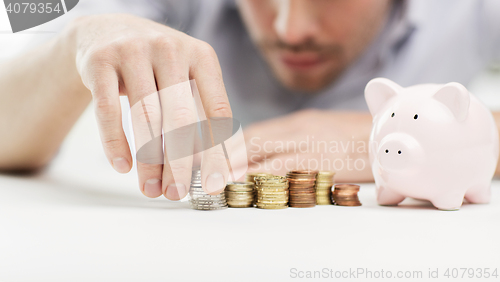 Image of close up of businessman with piggy bank and coins