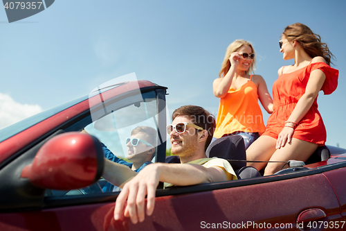 Image of happy friends driving in cabriolet car