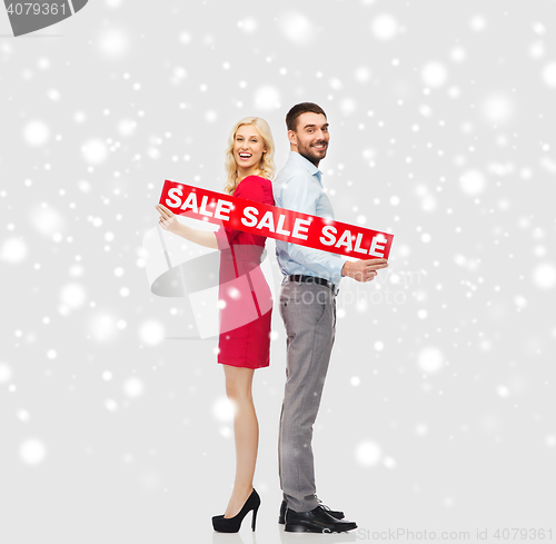 Image of happy couple with red sale sign over snow