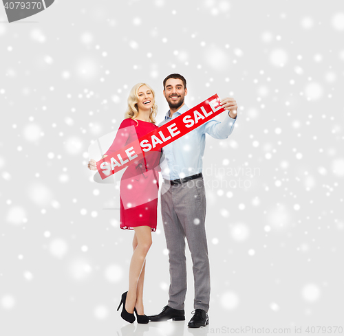 Image of happy couple with red sale sign over snow