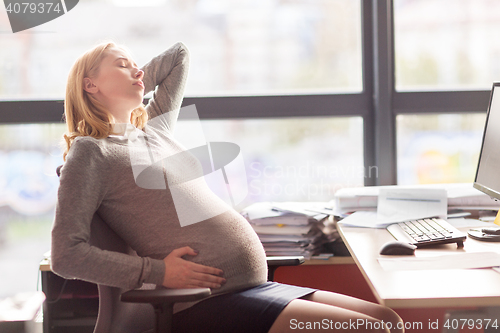 Image of pregnant businesswoman feeling sick at office work