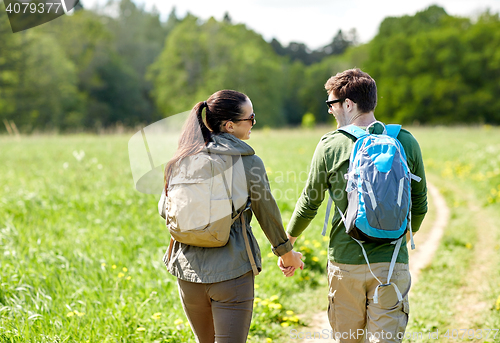 Image of happy couple with backpacks hiking outdoors