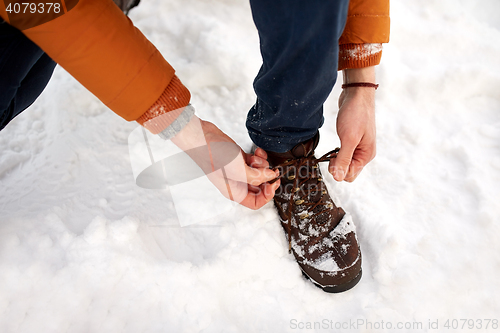 Image of close up of man tying boot shoelaces in winter