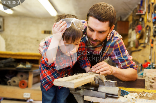 Image of father and little son with wood plank at workshop