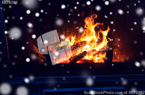 Image of close up of firewood burning in fireplace and snow