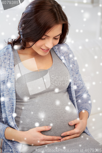 Image of happy pregnant woman sitting on sofa at home