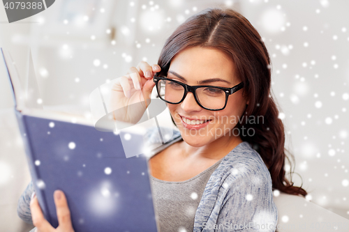 Image of happy woman in glasses reading book at home