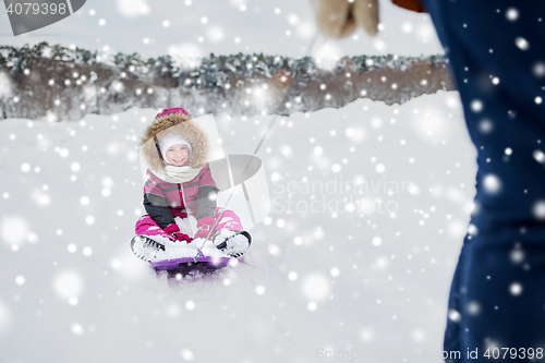 Image of parent carrying happy little kid on sled in winter