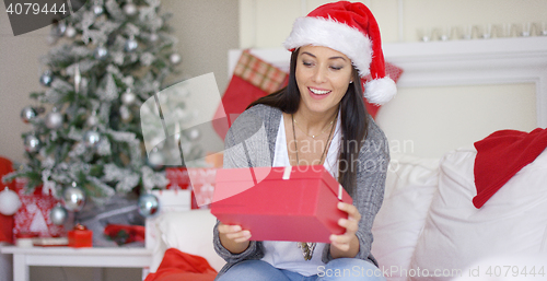 Image of Excited young woman opening a Christmas gift