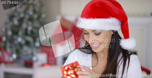 Image of Smiling woman unwrapping her Christmas gift