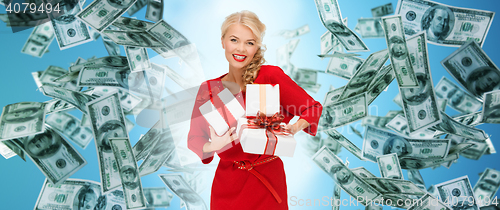 Image of happy woman in red with gifts over money rain