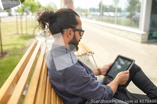 Image of man with tablet pc sitting on city street bench