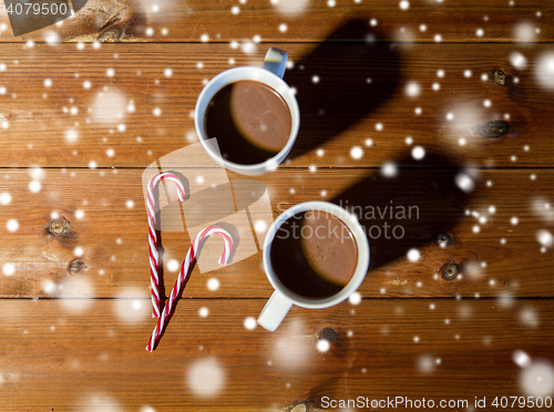 Image of christmas candy canes and cups on wooden table