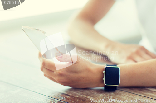 Image of close up of hands with smart phone and watch