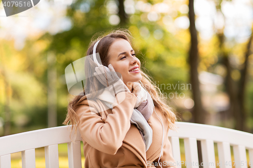 Image of happy woman with headphones in autumn park