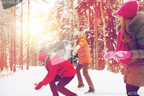 Image of happy friends playing snowball in winter forest