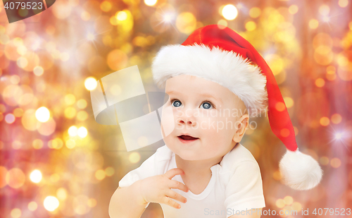 Image of baby boy in christmas santa hat over blue lights