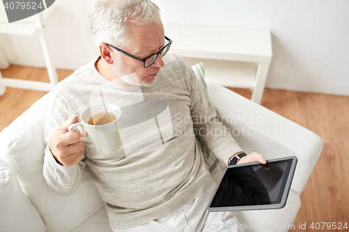 Image of senior man with tablet pc and tea cup at home
