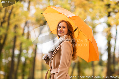 Image of happy woman with umbrella walking in autumn park