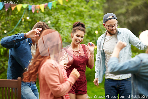 Image of happy friends dancing at summer party in garden
