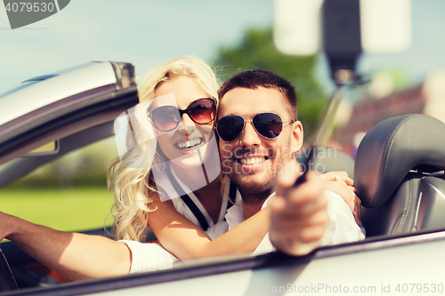 Image of happy couple in car taking selfie with smartphone