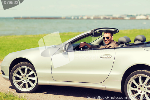 Image of happy man driving cabriolet car outdoors