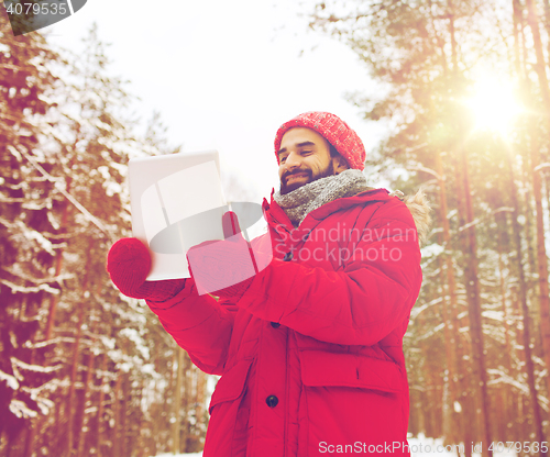 Image of happy man with tablet pc in winter forest