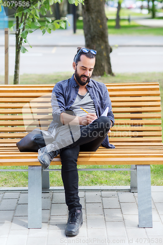 Image of man writing to notebook or diary on city street