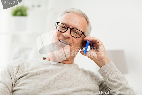Image of happy senior man calling on smartphone at home