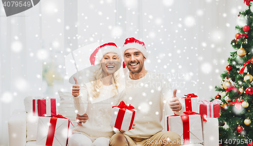 Image of happy couple with christmas gifts and thumbs up