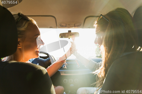 Image of happy teenage girls or women driving in car