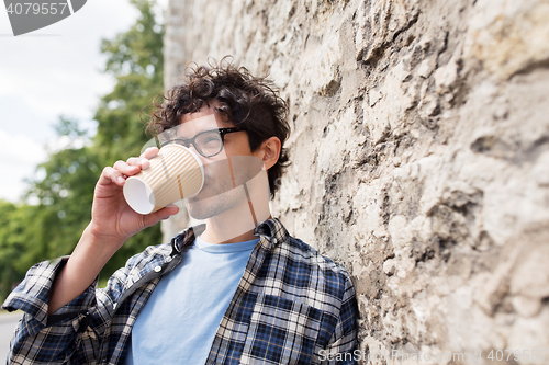 Image of man in eyeglasses drinking coffee over street wall