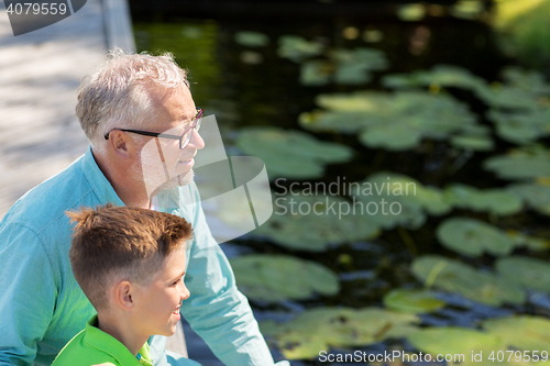 Image of grandfather and grandson sitting on river berth