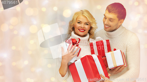 Image of happy couple in sweaters holding christmas gifts 