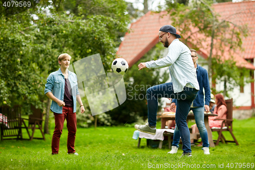 Image of happy friends playing football at summer garden