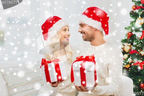 Image of happy couple at home exchanging christmas gifts