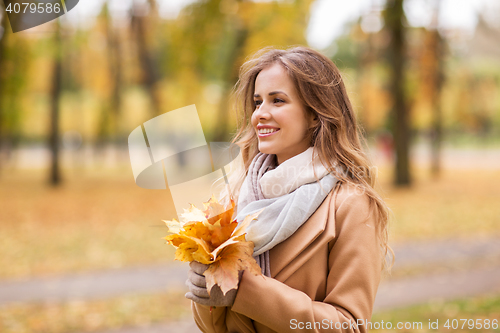 Image of beautiful woman with maple leaves in autumn park
