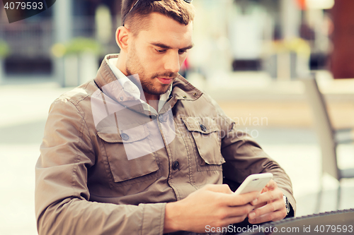 Image of man with smartphone at city street cafe